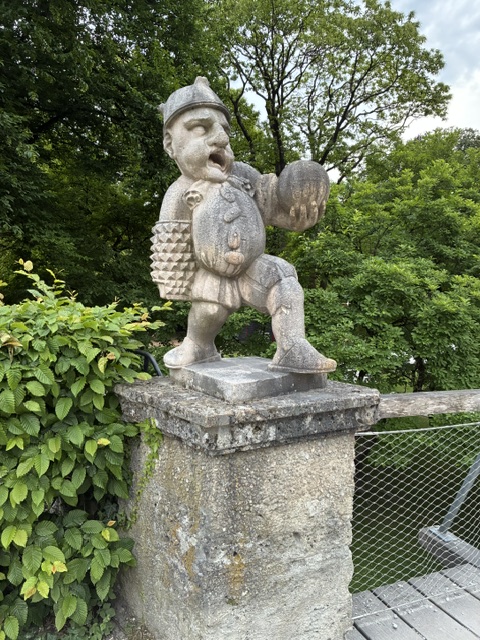 Stone statue of a dwarf with a spiked sleeve and a ball in the other hand.